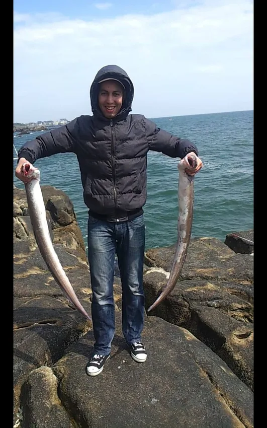 Adlene au bord de la mer, tenant deux poissons